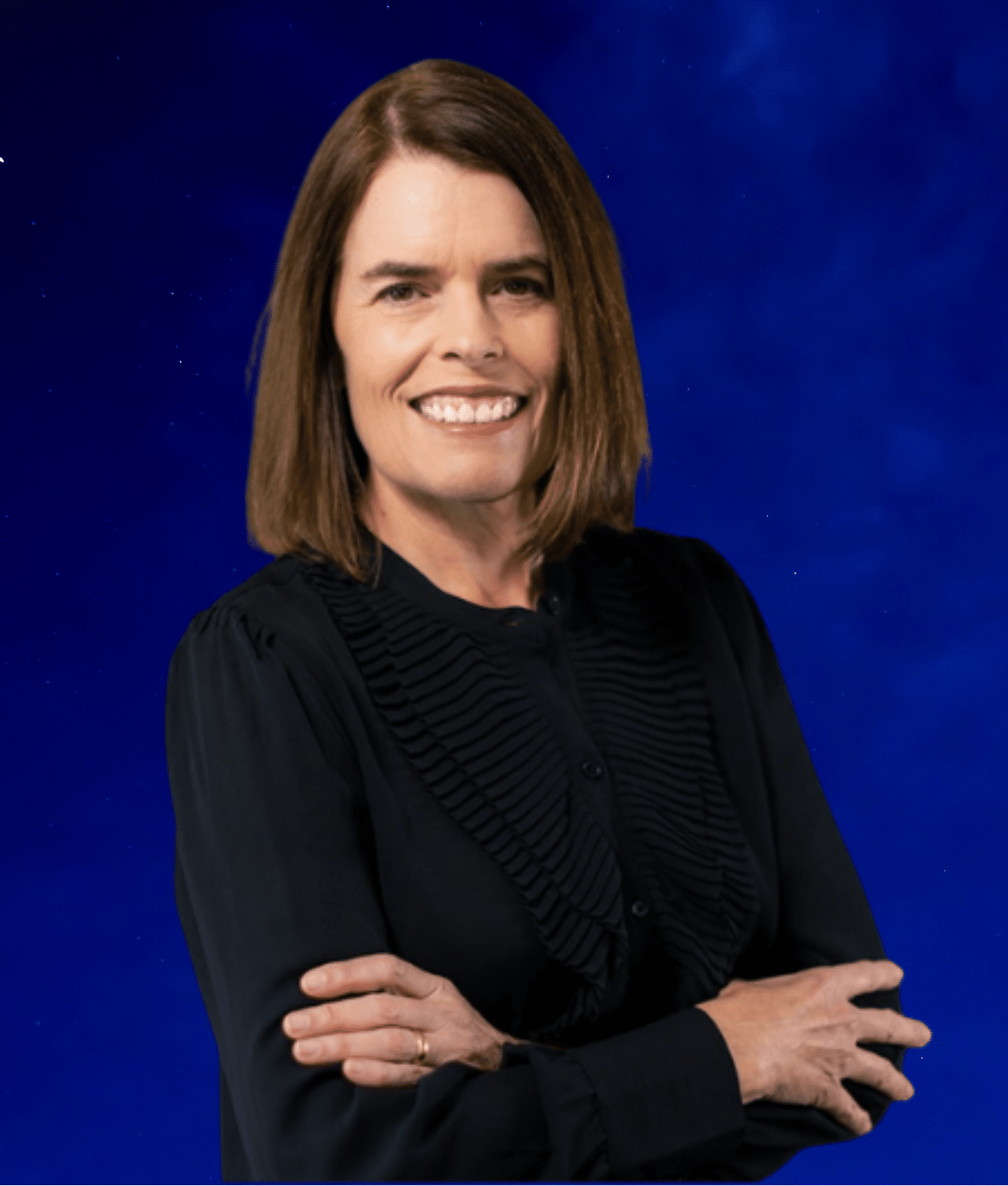 Smiling woman with brown hair and black shirt, arms crossed, on a blue background