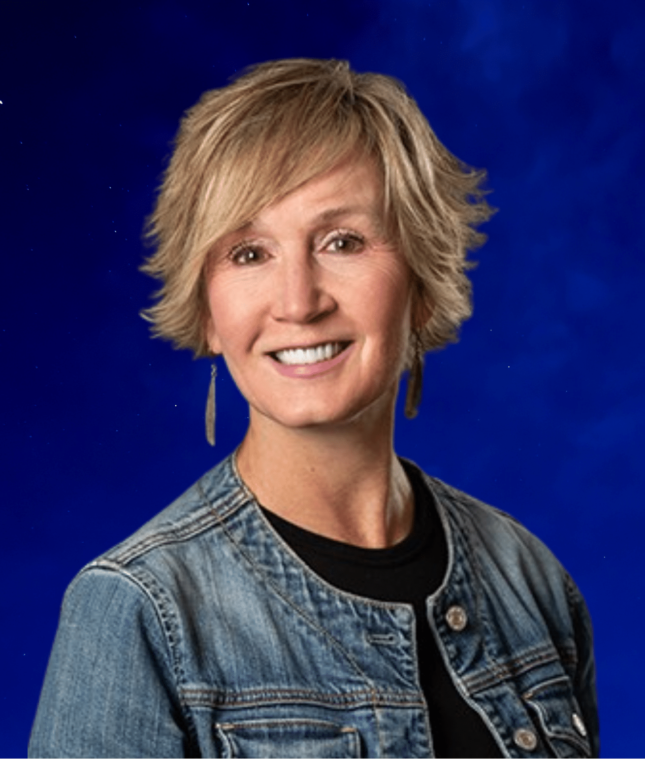 Tracie, a woman with short blonde hair smiling against a blue background