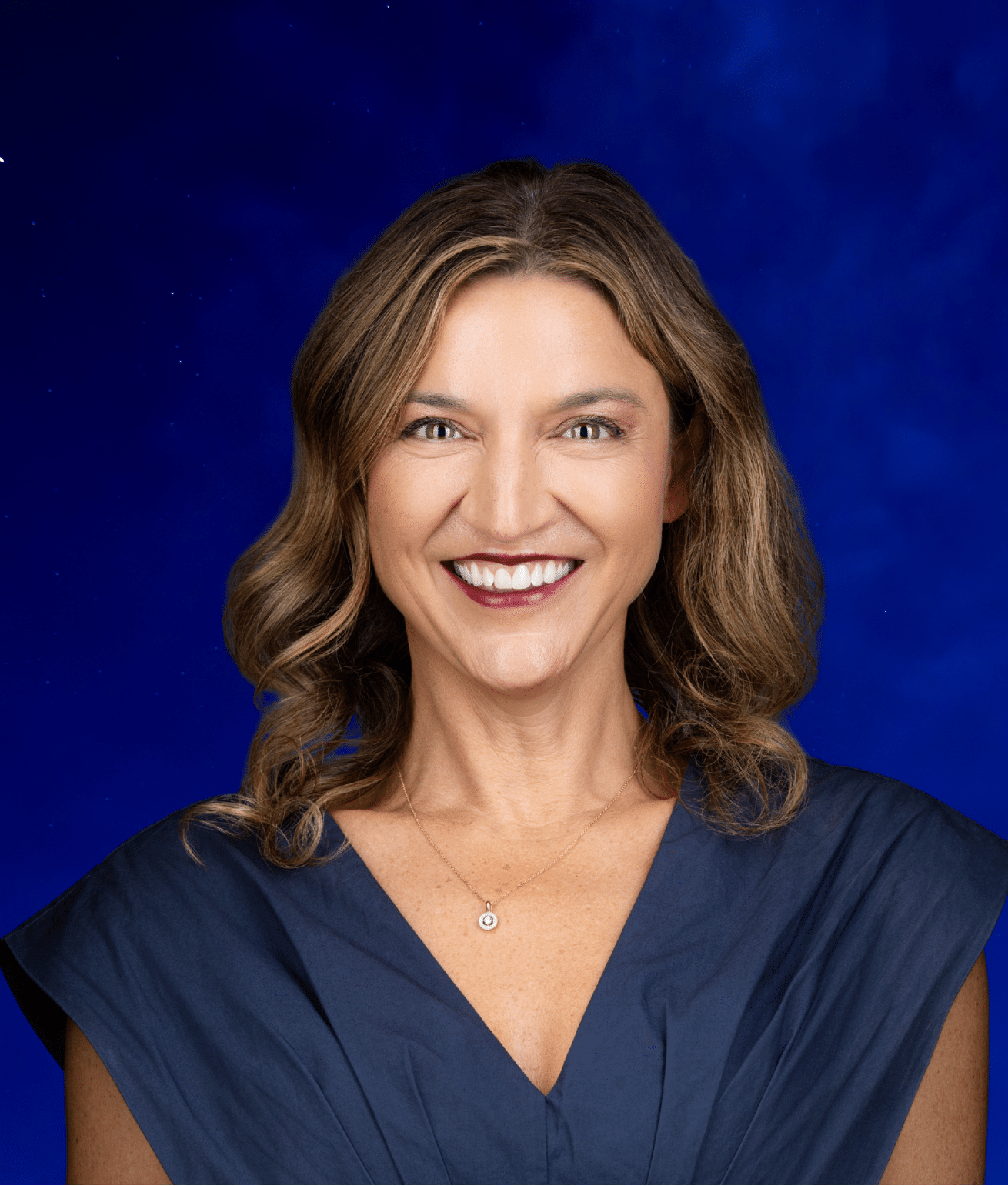 Jill, a smiling woman with shoulder-length brown hair, wearing a navy top and gold necklace